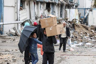 Palestinians carry boxes of aid provided by UNRWA, amid a ceasefire between Hamas and Israel, in Gaza City-stock-foto