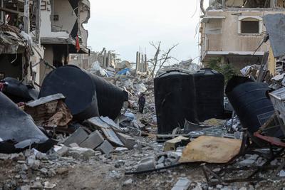 Palestinians walk along a street among the rubble of destroyed buildings amid a ceasefire between Israel and Hamas, in Gaza City-stock-foto