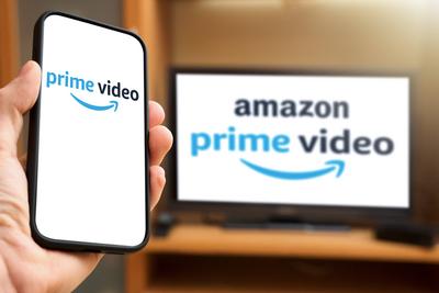 6 April 2024: Man holding smartphone with Prime Video logo in front of a TV set with Amazon Prime Video streaming provid-stock-foto