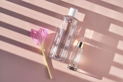 Flasche mit Gesichtswasser oder Reinigungsmittel auf einem rosa Hintergrund mit Streifen Schatten.-stock-photo