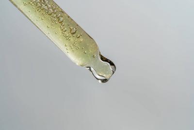 Nahaufnahme der Pipette mit 24r Gold Serum, Hyalurons?ure auf grauem Hintergrund. Konzept f?r Kosmetik und Gesundheitspflege. Dosis von ?therischen ?len, Retinol mit Luftblasen. Pr?sentation eines Sch?nheitsprodukts-stock-photo