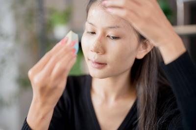 Asiatische Frau Anwendung Make-up-Stiftung und Concealer Make-up auf Gesicht mit Kosmetik Makeover T?gliche Sch?nheit Routine zu Hause.-stock-foto