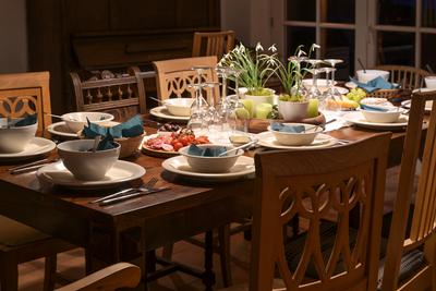 Large wooden table with various old chairs, festive set with white crockery, wine glasses and decoration for a casual di-stock-photo