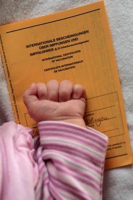 Babyhand und Impfpass . Wipperfuerth , Deutschland . Babyhand and vaccination certificate . Wipperfuerth , Germany . 17-stock-photo