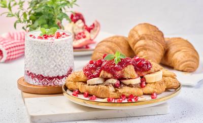 Croissant mit Schokolade, Bananenst?ckchen und Himbeermarmelade auf einem Teller-stock-foto