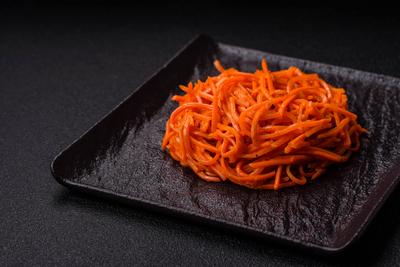 Tasty spicy Korean carrot with spices and herbs on a dark concrete background Tasty spicy Korean carrot with spices and-stock-foto