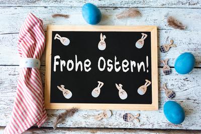27 March 2024: Easter greetings: Happy Easter! Schrfitzug on a blackboard on a rustic white table together with blue Eas-stock-foto