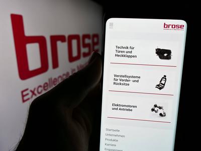 Person holding cellphone with webpage of German automotive company Brose Fahrzeugteile SE Co. KG. Stuttgart, Germany - 0-stock-photo