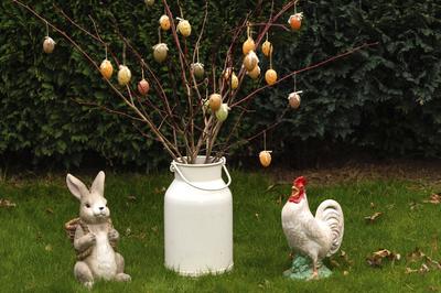 Ein Osterhase und Hahn aus Porzelan mit einem Osterstrau? mit Ostereiern im Garten. (Symbolfoto, Themenfoto) *** A porce-stock-foto