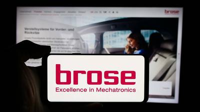 Person holding cellphone with logo of German automotive company Brose Fahrzeugteile SE Co. KG. Stuttgart, Germany - 08-0-stock-photo