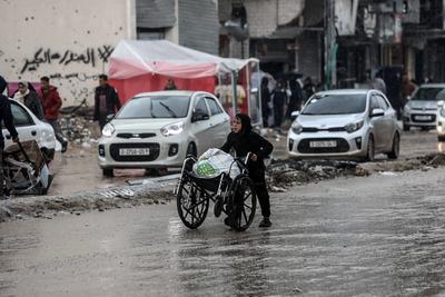 Palestinians walk through rubble during severe weather conditions in the Al-Rimal neighborhood in central Gaza City-stock-foto