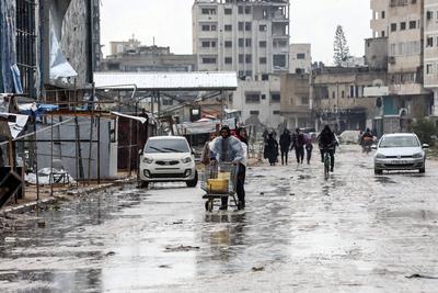 Palestinians walk through rubble during severe weather conditions in the Al-Rimal neighborhood in central Gaza City-stock-foto