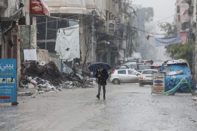 Palestinians walk through rubble during severe weather conditions in the Al-Rimal neighborhood in central Gaza City-stock-foto