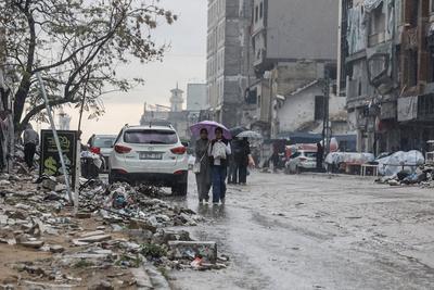 Palestinians walk through rubble during severe weather conditions in the Al-Rimal neighborhood in central Gaza City-stock-foto