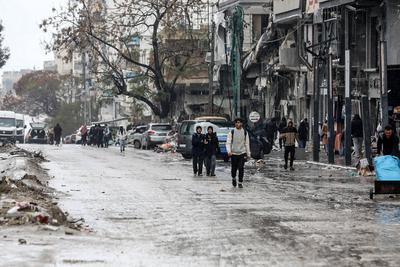 Palestinians walk through rubble during severe weather conditions in the Al-Rimal neighborhood in central Gaza City-stock-foto