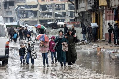 Palestinians walk through rubble during severe weather conditions in the Al-Rimal neighborhood in central Gaza City-stock-foto