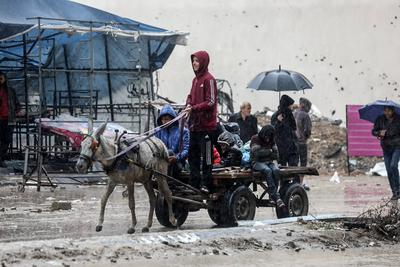 Palestinians walk through rubble during severe weather conditions in the Al-Rimal neighborhood in central Gaza City-stock-foto