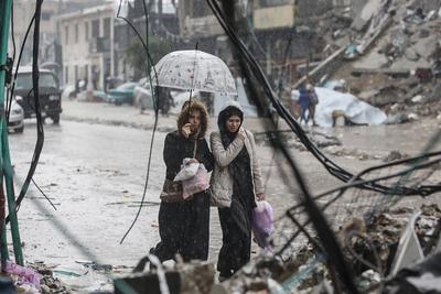 Palestinians walk through rubble during severe weather conditions in the Al-Rimal neighborhood in central Gaza City-stock-foto