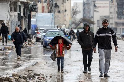 Palestinians walk through rubble during severe weather conditions in the Al-Rimal neighborhood in central Gaza City-stock-foto