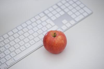 Symbolfoto zum Thema ??? Gesunde Ernaehrung am Arbeitsplatz ??? . Ein Apfel liegt neben einer Tastatur auf einem Schreib-stock-foto