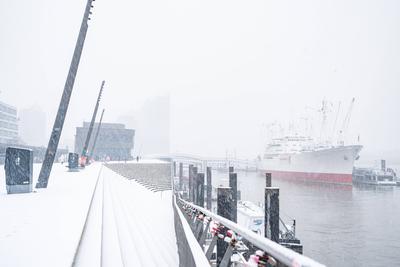 Winterimpression ? Schneefall am Hamburger Hafen ? Jan-Fedder-Promenade mit Blick auf die Elbphilharmonie im Nebel-stock-foto
