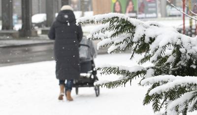 Wintereinbruch in Hamburg. Eine Frau geht bei dichtem Schneefall mit ihrem Kinderwagen auf einem Gehweg entlang. Winterh-stock-foto
