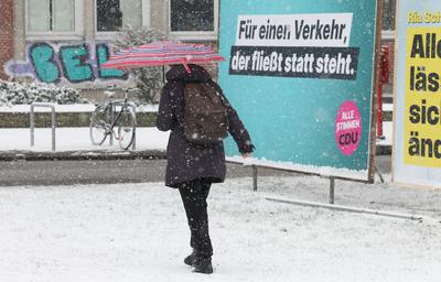 Wintereinbruch in Hamburg. Eine Frau geht bei dichtem Schneefall mit einem Regenschirm auf einem Gehweg entlang. Barmbek-stock-foto