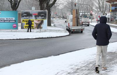Ein Plakatierer klebt auf einer Verkehrsinsel ein Plakat von Christian Lindner, Bundesvorsitzender der Partei Freie Demo-stock-foto