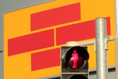 rote Fu?g?ngerampel vor dem Emblem der Bausparkasse Schw?bisch Hall am Unternehmenssitz Hohenlohe-stock-foto