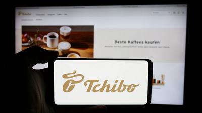 Person holding cellphone with logo of German coffee retail company Tchibo GmbH in front of website. Stuttgart, Germany --stock-foto