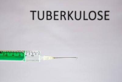 This photo illustration shows a disposable syringe with hypodermic needle, TUBERKULOSE written on a white board behind G-stock-photo