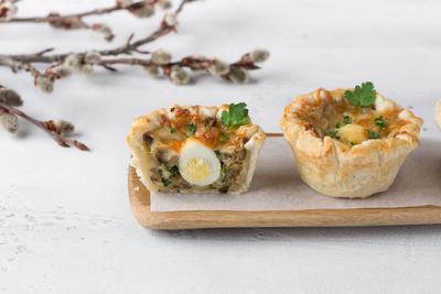 Pilz-Julienne mit Wachtelei und K?se in einem Bl?tterteigkorb auf hellblauem Hintergrund. Ostern Stil mit Weidenzweigen-stock-photo
