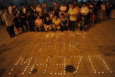 Malaysians pose behind a slogan Pray for MH370 made of candles during a vigil for the missing Malays-stock-foto
