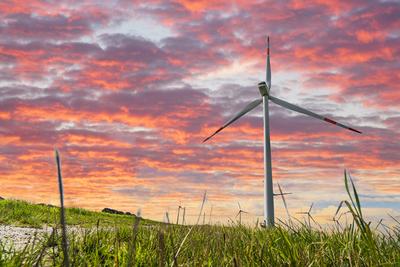Bavaria, Germany - 11 February 2025: PHOTOMONTAGE, wind turbine on a green meadow in front of a colorful sunset symboliz-stock-foto