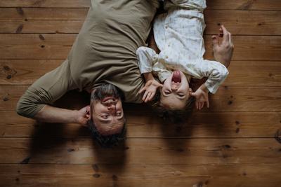 Top view of father with daughter lying on floor laughing together. Girls dad. Unconditional paternal love, Father s Day-stock-photo