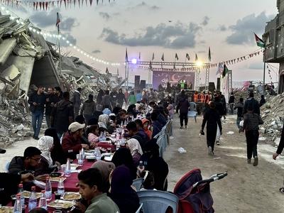 Palestinians break their fast by eating the Iftar meals during the holy month of Ramadan, near the rubble of buildings, amid a ceasefire between Israel and Hamas, in Rafah-stock-foto