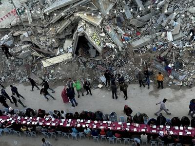 Palestinians break their fast by eating the Iftar meals during the holy month of Ramadan, near the rubble of buildings, amid a ceasefire between Israel and Hamas, in Rafah-stock-foto