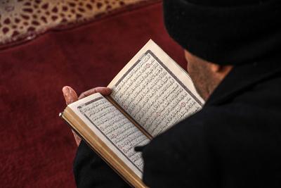 Muslim worshippers read from the Holy Quran as they sit at the historic Al-Omari Mosque in Gaza City on the second day of the holy month of Ramadan-stock-foto