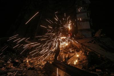 Palestinian youths light fireworks near the ruins of a building to celebrate the second day of the holy month of Ramadan in the Al-Rimal neighborhood in central Gaza City-stock-foto