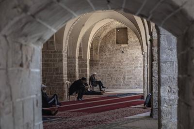 Muslim worshippers read from the Holy Quran as they sit at the historic Al-Omari Mosque in Gaza City on the second day of the holy month of Ramadan-stock-foto