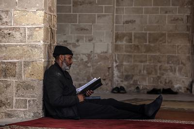 Muslim worshippers read from the Holy Quran as they sit at the historic Al-Omari Mosque in Gaza City on the second day of the holy month of Ramadan-stock-foto