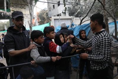 Palestinians go about their daily lives past destroyed buildings at the Nuseirat refugee camp-stock-foto