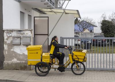 Deutsche Post, DHL profitiert vom Online-Handel. Paketzustellerin auf ihrem Dienstsfahrrad. // 24.02.2025: Karlsruhe, Ba-stock-foto