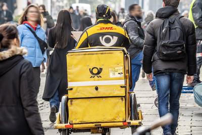 Postbote mit gelbem Dienstfahrrad in der Innenstadt unterwegs, M?nchen, Februar 2025-stock-photo