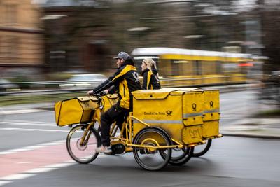 Zwei Brieftr?ger der Deutschen Post fahren mit ihren Lastenfahrr?dern durch Berlin-Prenzlauer Berg. / Two Deutsche Post-stock-foto
