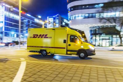 Lieferfahrzeug von DHL. Auto bei Nacht vor urbaner Umgebung mit moderner Architektur, Mitzieher. // 03.02.2025: Stuttgar-stock-foto