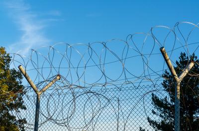 A close-up view of a tall barbed wire fence on the border between Turkey and Bulgaria A close-up view of a tall barbed w-stock-foto