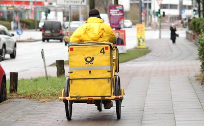 Ein Briefzusteller der Deutschen Post f?hrt mit seinem Fahrrad auf einem Gehweg entlang. Wandsbek Hamburg *** A Deutsche-stock-foto