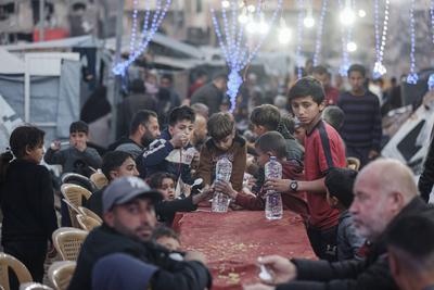 Palestinians gather among destroyed buildings to break their fast together during the holy month of Ramadan in Jabalia camp, northern Gaza Strip-stock-foto