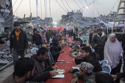 Palestinians gather among destroyed buildings to break their fast together during the holy month of Ramadan in Jabalia camp, northern Gaza Strip-stock-foto